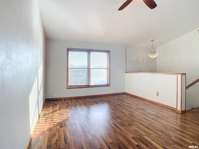 unfurnished room featuring ceiling fan with notable chandelier and dark wood-type flooring