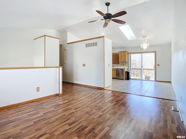 unfurnished living room with a skylight, ceiling fan with notable chandelier, dark hardwood / wood-style floors, and high vaulted ceiling