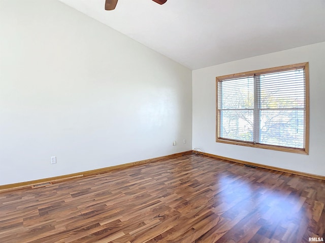 spare room with ceiling fan, dark wood-type flooring, and vaulted ceiling