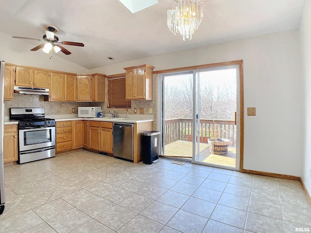 kitchen featuring sink, lofted ceiling with skylight, decorative light fixtures, light tile patterned floors, and appliances with stainless steel finishes