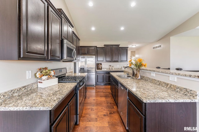 kitchen with sink, light stone counters, appliances with stainless steel finishes, dark brown cabinets, and dark hardwood / wood-style flooring