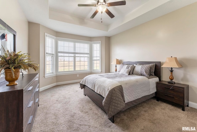 bedroom featuring light carpet, a tray ceiling, and ceiling fan