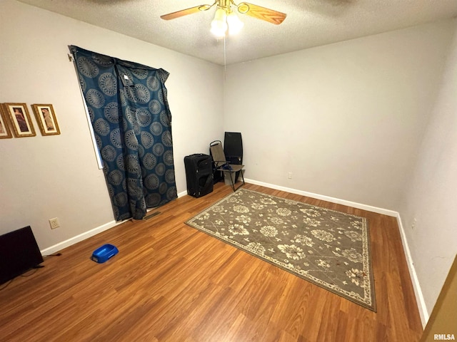 interior space featuring ceiling fan, a textured ceiling, and hardwood / wood-style flooring