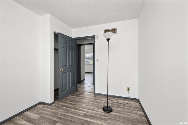 unfurnished room featuring a textured ceiling and hardwood / wood-style flooring