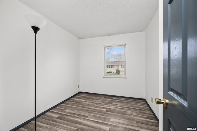 unfurnished room with a textured ceiling and dark wood-type flooring