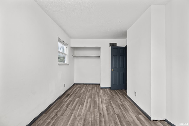 unfurnished bedroom with a closet, hardwood / wood-style floors, and a textured ceiling