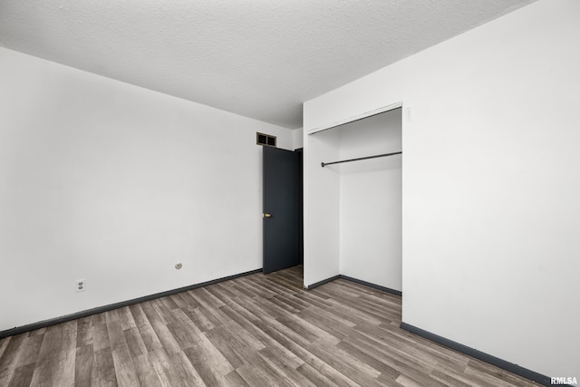 unfurnished bedroom featuring a textured ceiling, light wood-type flooring, and a closet