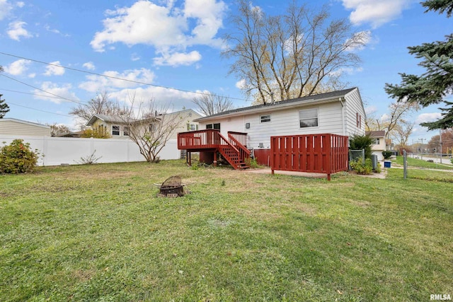 back of property featuring a fire pit, a lawn, and a wooden deck