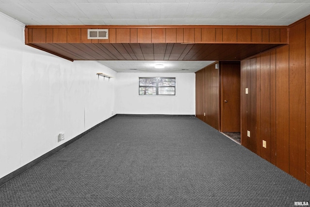 basement with dark colored carpet and wood walls