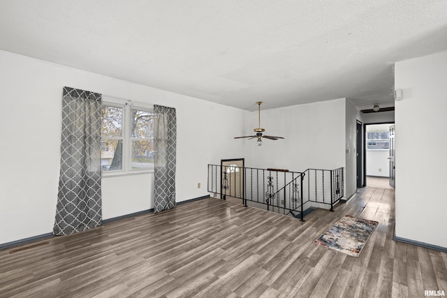 unfurnished room with a textured ceiling, hardwood / wood-style flooring, and ceiling fan