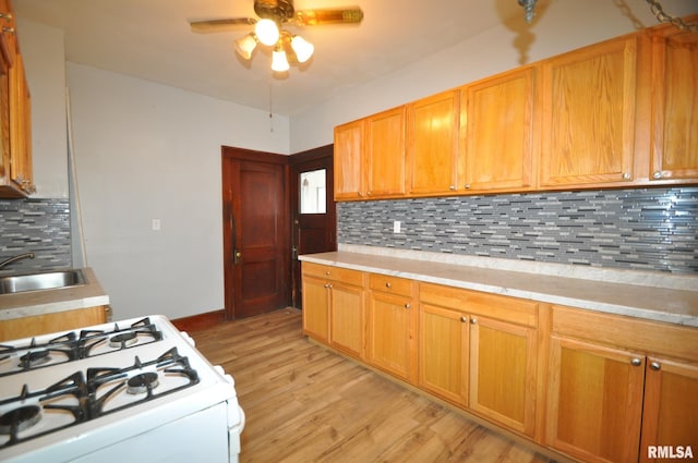 1815 Belle Ave, Davenport, IA 52803 - kitchen with white range with gas stovetop, a sink, a ceiling fan, light countertops, and light wood-style flooring