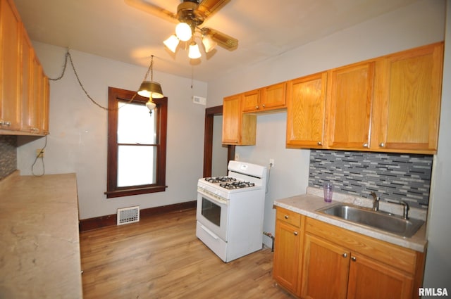 1815 Belle Ave, Davenport, IA 52803 - kitchen with white range with gas cooktop, a sink, a ceiling fan, light countertops, and tasteful backsplash