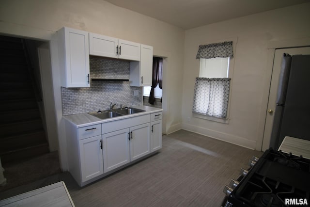 kitchen with white cabinets, stainless steel fridge, backsplash, and sink