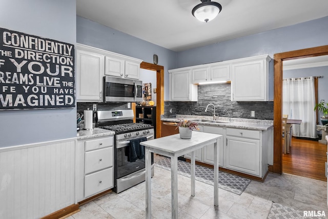 kitchen with white cabinets, stainless steel appliances, light stone countertops, and sink