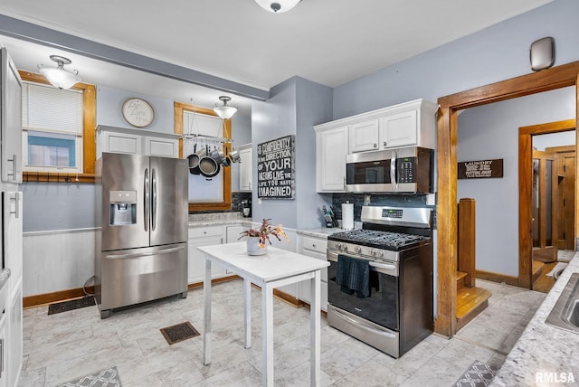 kitchen with stainless steel appliances, white cabinetry, tasteful backsplash, and light stone counters