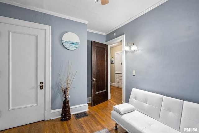 sitting room featuring ceiling fan, wood-type flooring, and ornamental molding