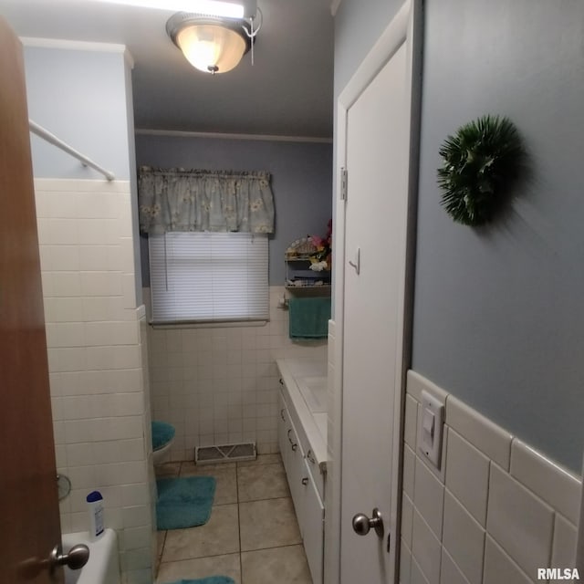 bathroom with toilet, tile patterned flooring, tile walls, and ornamental molding