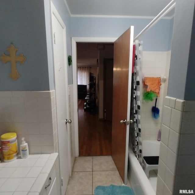 bathroom with tile patterned floors, shower / bath combo with shower curtain, and tile walls