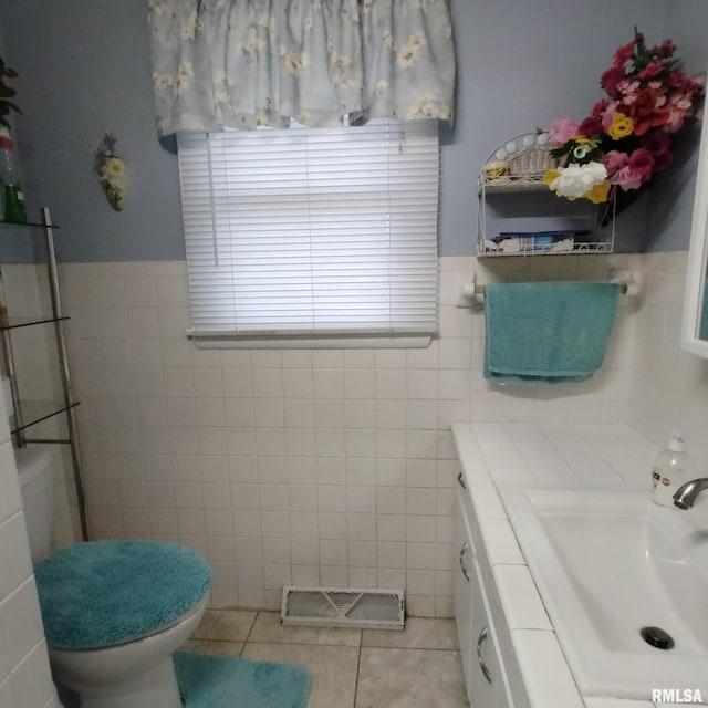 bathroom featuring toilet, vanity, tile patterned floors, and tile walls