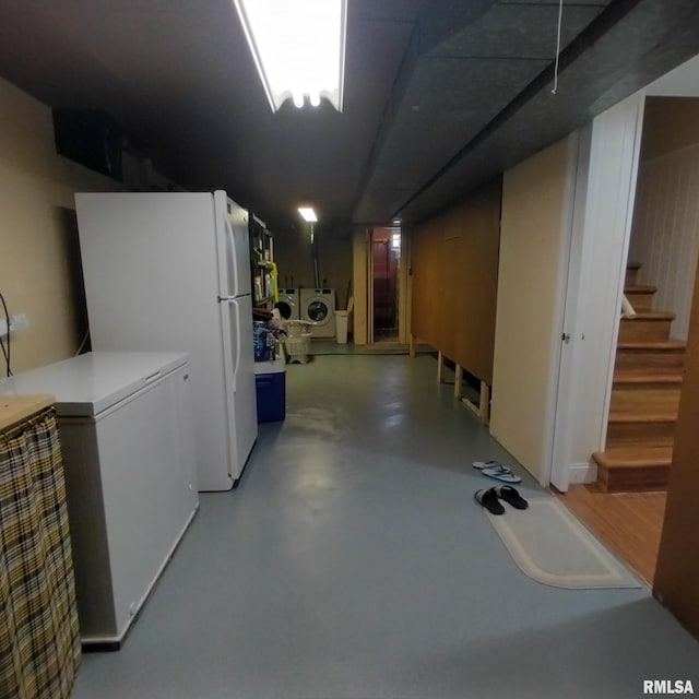 basement featuring white refrigerator, fridge, and washer and clothes dryer