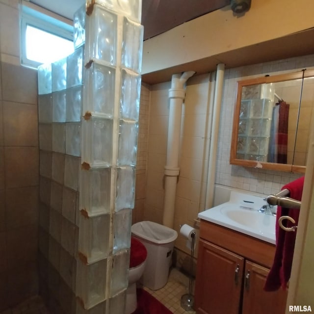 bathroom with backsplash, a shower, toilet, vanity, and tile walls