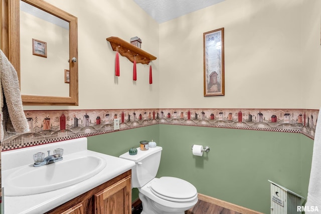 bathroom featuring toilet, vanity, a textured ceiling, and hardwood / wood-style flooring