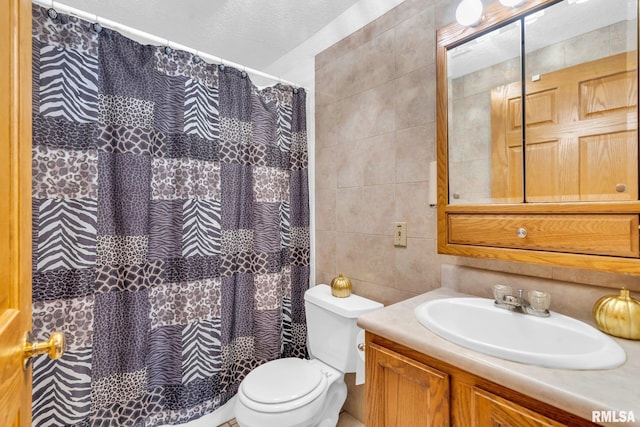 bathroom with vanity, a shower with curtain, toilet, a textured ceiling, and tile walls