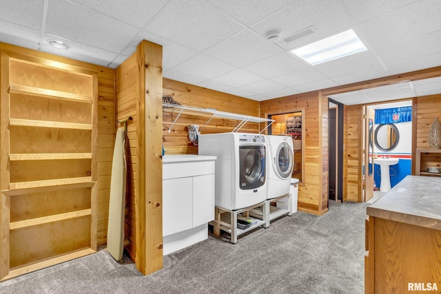 clothes washing area with carpet, cabinets, wooden walls, and washing machine and clothes dryer