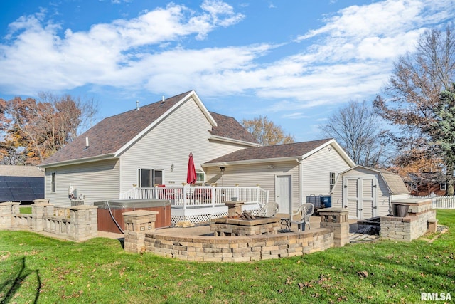 back of property featuring a wooden deck, a fire pit, a yard, and a hot tub