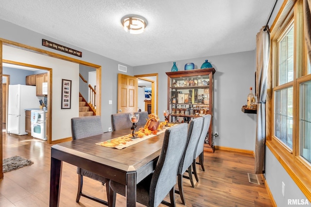 dining space featuring a wealth of natural light, light hardwood / wood-style flooring, and a textured ceiling