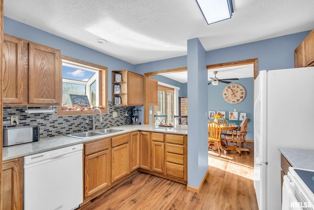 kitchen with sink, a textured ceiling, white appliances, decorative backsplash, and light wood-type flooring