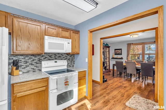 kitchen with tasteful backsplash, light hardwood / wood-style flooring, and white appliances