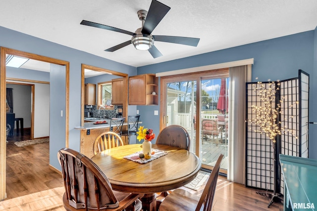 dining area featuring ceiling fan, a textured ceiling, and light wood-type flooring