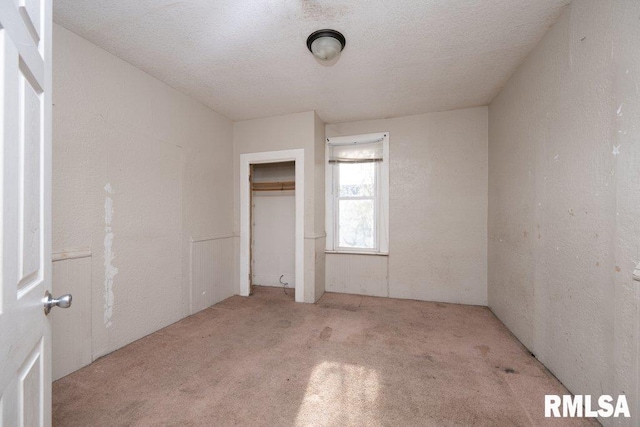 unfurnished bedroom with light carpet, a closet, and a textured ceiling