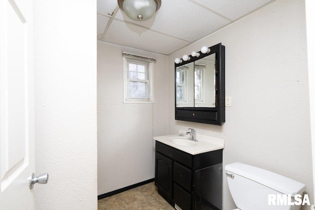 bathroom with a paneled ceiling, vanity, and toilet