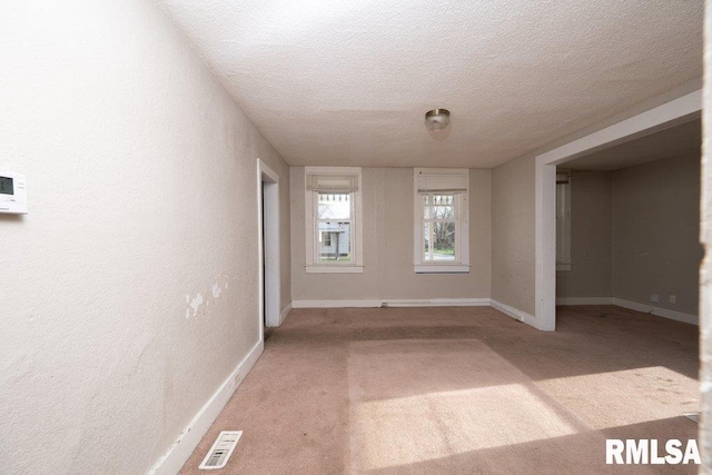 unfurnished room with a textured ceiling and light colored carpet