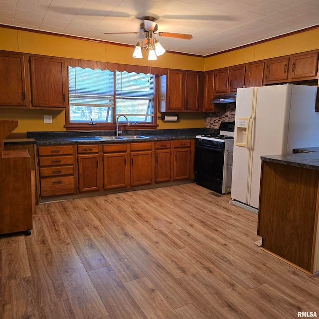 kitchen featuring sink, white fridge with ice dispenser, ceiling fan, light hardwood / wood-style floors, and gas stove