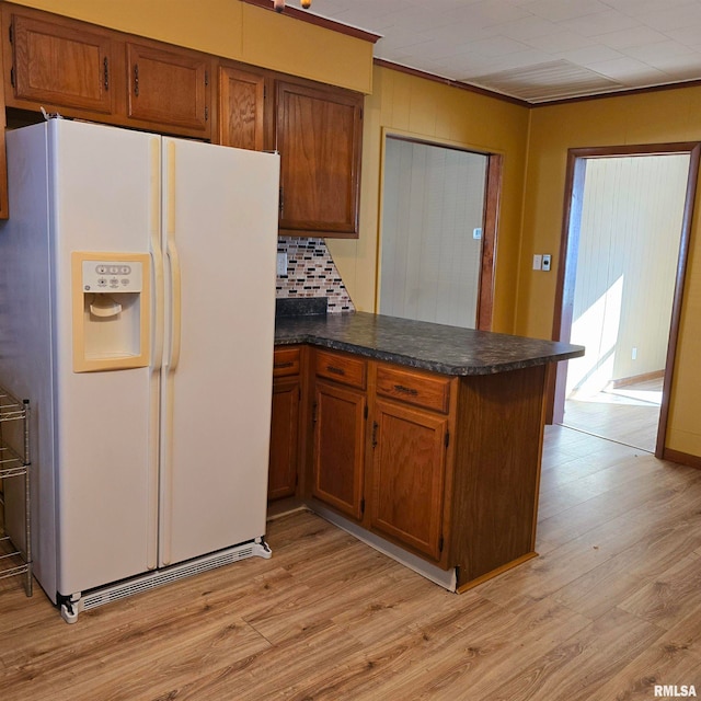 kitchen featuring decorative backsplash, white refrigerator with ice dispenser, light hardwood / wood-style floors, kitchen peninsula, and crown molding