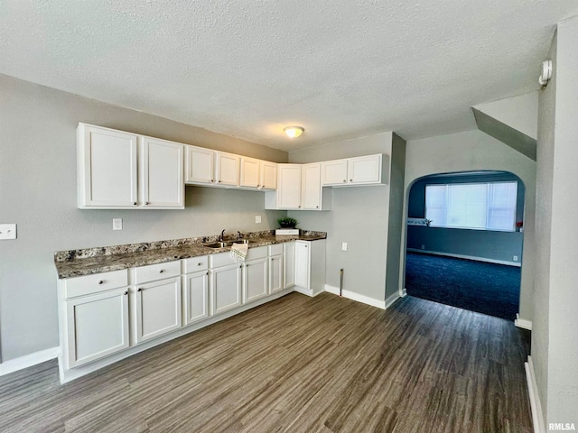 kitchen with dark stone countertops, hardwood / wood-style floors, white cabinets, and a textured ceiling