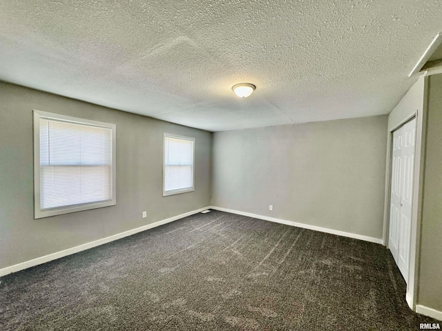 interior space featuring a textured ceiling and dark carpet