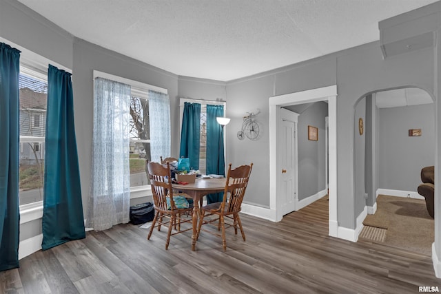 dining room with hardwood / wood-style floors, a textured ceiling, and ornamental molding