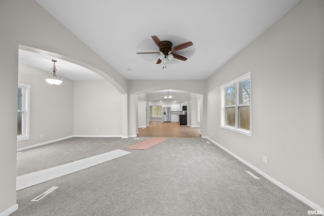 unfurnished living room with ceiling fan, carpet floors, and lofted ceiling