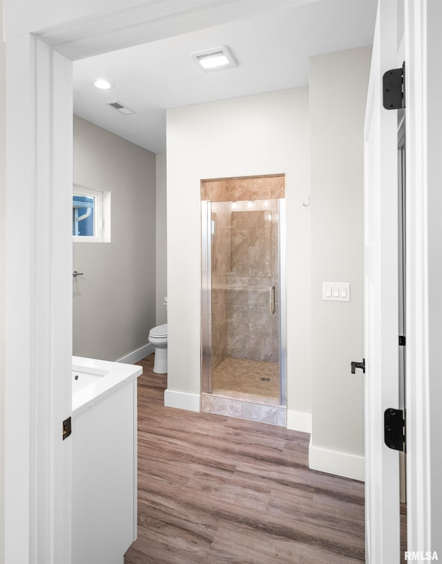 bathroom with wood-type flooring, vanity, toilet, and an enclosed shower