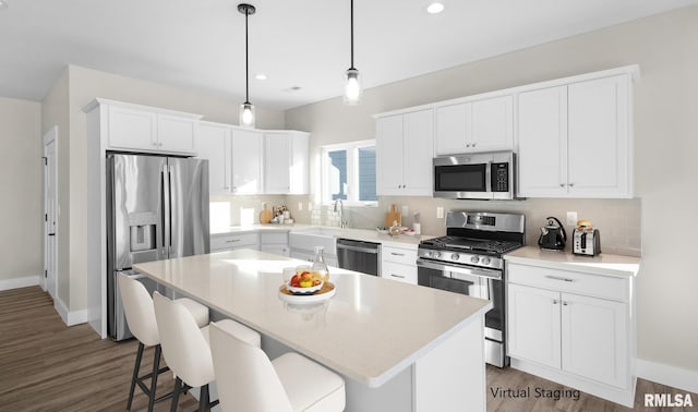 kitchen featuring a kitchen island, appliances with stainless steel finishes, decorative light fixtures, white cabinets, and light wood-type flooring