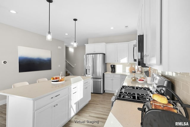 kitchen with appliances with stainless steel finishes, a center island, white cabinetry, and pendant lighting