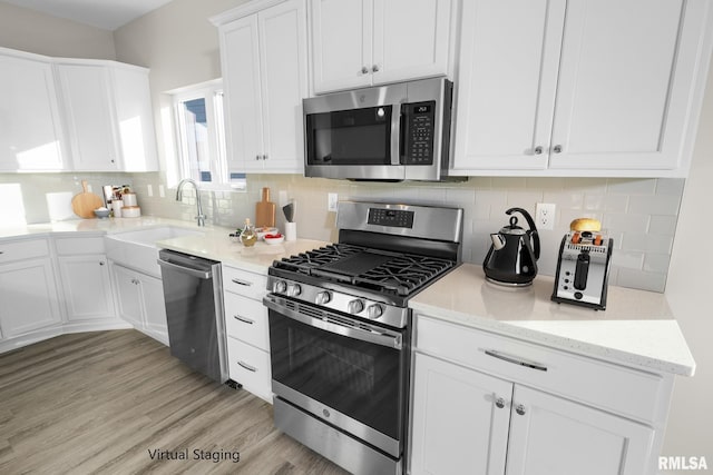 kitchen featuring white cabinetry, sink, light hardwood / wood-style flooring, backsplash, and appliances with stainless steel finishes