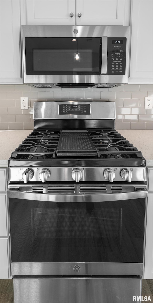 interior details with white cabinets, appliances with stainless steel finishes, and decorative backsplash