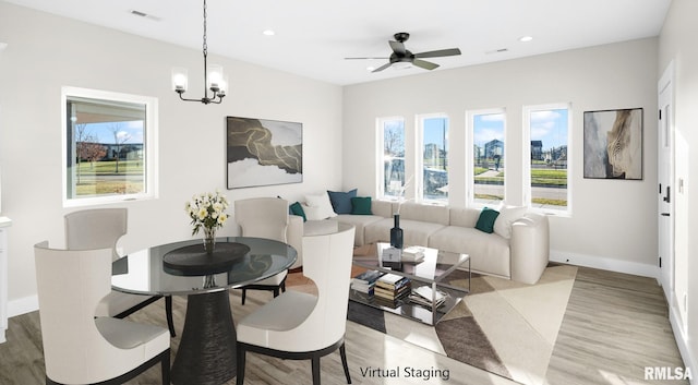 living room with ceiling fan with notable chandelier and light hardwood / wood-style floors