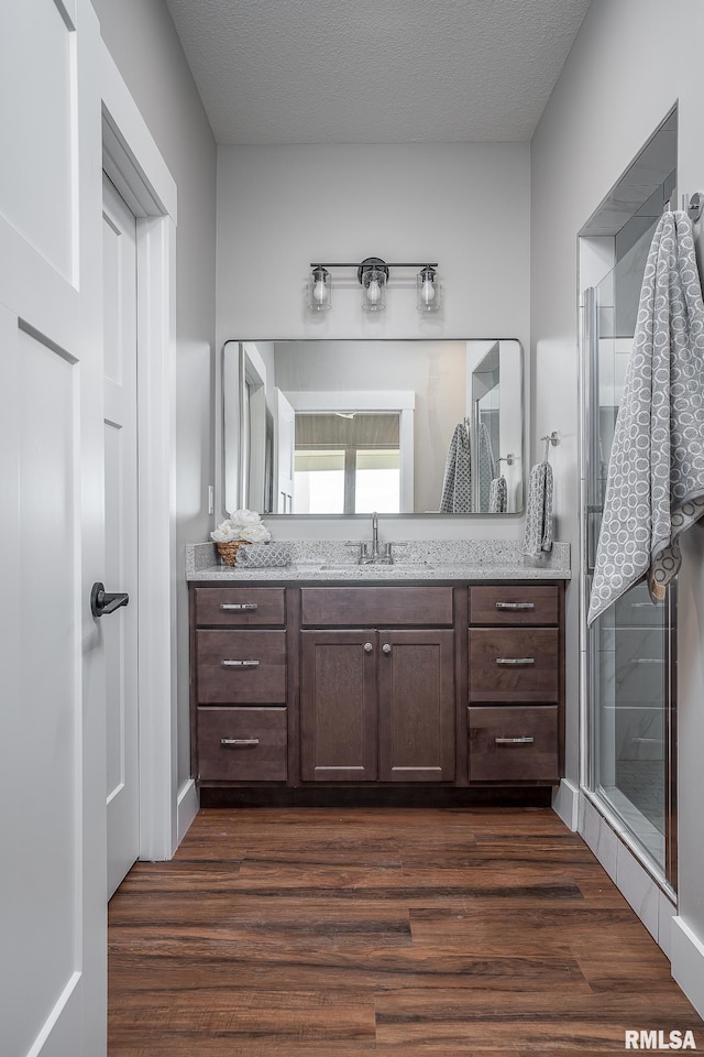 bathroom with hardwood / wood-style flooring, vanity, an enclosed shower, and a textured ceiling