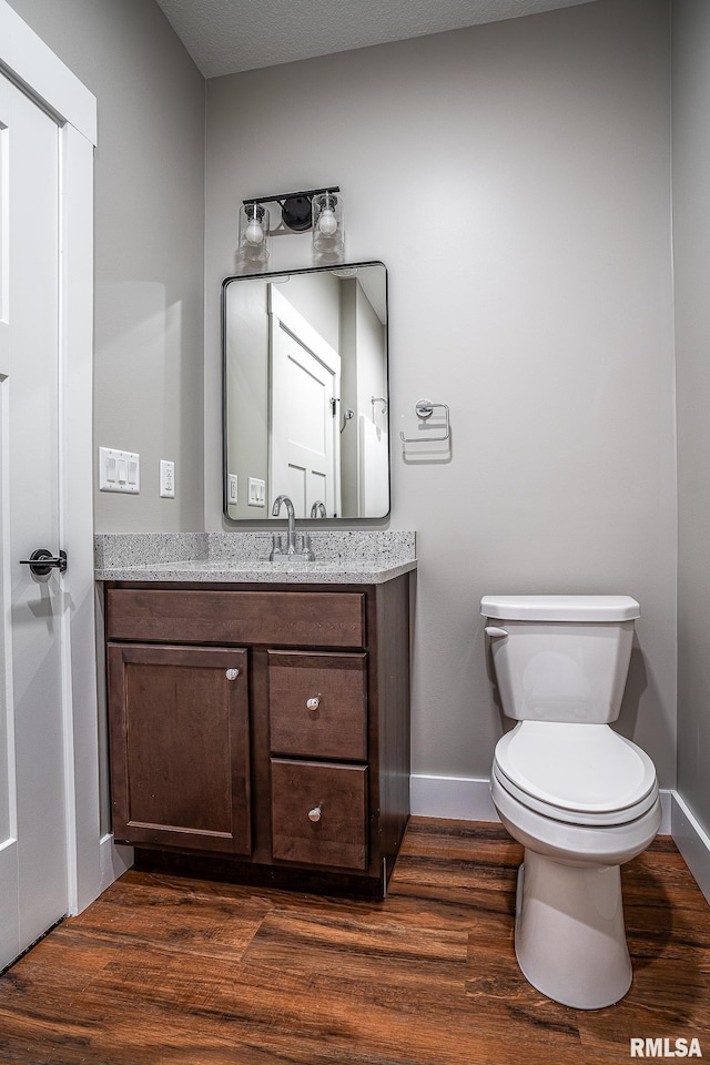 bathroom featuring toilet, vanity, a textured ceiling, and hardwood / wood-style flooring